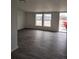 Living room with new gray flooring, fresh white paint, two large windows, and a glass panel exterior door at 7486 Harold St, Fort Lupton, CO 80621