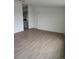 Living room with gray flooring, fresh paint, white trim, interior door, and the kitchen visible at 7486 Harold St, Fort Lupton, CO 80621