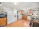 Functional kitchen featuring white appliances, wood cabinets, and laminate floors near the staircase at 3726 Decatur St, Denver, CO 80211