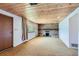 A basement with a brick fireplace and door to outside featuring a wood paneled ceiling and carpeted floor at 7785 Westview Dr, Lakewood, CO 80214
