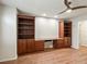 Spacious home office featuring laminate flooring, neutral paint, built-in shelving, and a ceiling fan at 8579 S Miller Way, Littleton, CO 80127