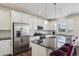 Modern kitchen featuring white cabinets, stainless steel appliances, granite countertops and stylish bar stools at 12797 Clearview St, Firestone, CO 80504