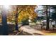A long curved driveway leading through a scenic landscape with autumn foliage and quaint structures at 1075 Dudley St, Lakewood, CO 80215