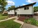Charming home featuring light green siding, a brick foundation, and a well-maintained front yard and walkway at 1075 Dudley St, Lakewood, CO 80215