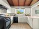 Bright kitchen with light cabinetry, wood-beam ceilings, and a large window overlooking the yard at 1075 Dudley St, Lakewood, CO 80215