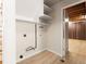 Small laundry area with shelving and access to unfinished basement at 1075 Dudley St, Lakewood, CO 80215