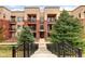 A stylish three-story apartment complex with brick and light brown walls and black iron balconies at 303 Inverness S Way # 101, Englewood, CO 80112