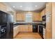 Galley-style kitchen with light wood cabinets and black appliances at 9543 Pearl Cir # 101, Parker, CO 80134