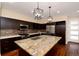 This kitchen features dark cabinets, a granite countertop island, stainless steel appliances and pendant lighting at 3390 Cranston Cir, Highlands Ranch, CO 80126