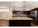 This kitchen features dark cabinets, a granite countertop island, stainless steel appliances and pendant lighting at 3390 Cranston Cir, Highlands Ranch, CO 80126