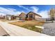 A single story home with a tan exterior and two car garage and partially xeriscaped front yard at 10266 Stagecoach Ave, Firestone, CO 80504