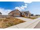 Side view of a tan home with a two car garage and xeriscaped yard in suburban neighborhood at 10266 Stagecoach Ave, Firestone, CO 80504