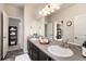 Bathroom featuring double sink vanity and mirrors and views into the hallway with closet shelving at 6370 Twilight Ave, Firestone, CO 80504