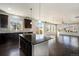 Modern kitchen with a large island, dark cabinetry, hardwood floors and an open floor plan leading to the living room at 6370 Twilight Ave, Firestone, CO 80504