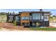 Modern home with stone and wood facade, large windows, balcony, and beautifully landscaped yard at 11115 Evening Hunt Rd, Franktown, CO 80116