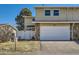 Tan two-story home featuring a two-car garage, white fence, and green grass at 2446 S Vaughn Way # A, Aurora, CO 80014