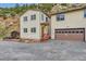 Exterior elevation of home with gravel driveway, a small front porch, garage, and partial hillside view at 4 Virginia St, Idaho Springs, CO 80452