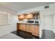 Functional kitchenette features wooden cabinetry and leads to both the living area and front door at 7000 E Quincy Ave # 317, Denver, CO 80237