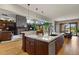 Open-concept kitchen with a large island, stone fireplace, and seamless connection to the living room at 4839 Bandera Pl, Parker, CO 80134