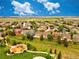 A stunning aerial view of a colorful community with a playground and expansive green space under a bright blue sky at 11649 E 111Th Ave, Commerce City, CO 80640