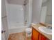 This bathroom has a shower over the tub, tile flooring and wooden cabinets with a sink at 11649 E 111Th Ave, Commerce City, CO 80640