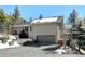 Two story home features a gray garage door, driveway, and partial snow coverage surrounded by tall trees at 2218 Witter Gulch Rd, Evergreen, CO 80439