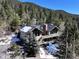 Mountain home featuring a deck, stone chimney, and surrounded by pine trees at 2218 Witter Gulch Rd, Evergreen, CO 80439