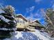 Mountain chalet home boasting large windows, wood siding, and snowy surroundings offering serene views at 2218 Witter Gulch Rd, Evergreen, CO 80439