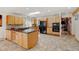 Open kitchen with stone tile flooring, light wood cabinetry, a black refrigerator and center island with black countertop at 2218 Witter Gulch Rd, Evergreen, CO 80439