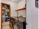 Laundry area featuring modern front load washer and dryer, tiled floor, and storage shelves at 2218 Witter Gulch Rd, Evergreen, CO 80439