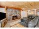 Living room with stone fireplace, wood ceilings, and comfortable couch for relaxing and entertaining at 2218 Witter Gulch Rd, Evergreen, CO 80439