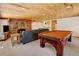 Spacious living room featuring stone fireplace, pool table, and wood ceiling at 2218 Witter Gulch Rd, Evergreen, CO 80439