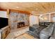 Living room featuring a stone fireplace, leather couch, and kitchenette with wood ceiling at 2218 Witter Gulch Rd, Evergreen, CO 80439