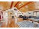 Open concept living room with hardwood floors, vaulted wood ceilings, and adjacent wet bar at 2218 Witter Gulch Rd, Evergreen, CO 80439