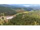 Aerial view of horse property paddocks, barn, and pastures, bordered by the lush forests of the Colorado mountains at 2013 Swede Gulch Rd, Evergreen, CO 80439