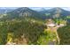 Scenic aerial view of horse property with riding paddocks nestled amongst pine trees in the Colorado mountain range at 2013 Swede Gulch Rd, Evergreen, CO 80439