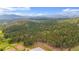 Sweeping aerial perspective of treed acreage featuring horse property, paddocks, and mountain views in Colorado at 2013 Swede Gulch Rd, Evergreen, CO 80439