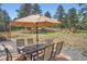 Backyard dining area with umbrella for shade and a view of surrounding forest trees at 2013 Swede Gulch Rd, Evergreen, CO 80439