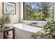 Relaxing bathroom featuring a modern standalone bathtub with a scenic view of the surrounding greenery at 2013 Swede Gulch Rd, Evergreen, CO 80439