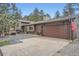 Charming exterior with a two-car garage, gravel driveway, and stone chimney at 2013 Swede Gulch Rd, Evergreen, CO 80439