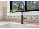 Close-up of modern kitchen faucet, decorative backsplash, and stone countertops at 2013 Swede Gulch Rd, Evergreen, CO 80439