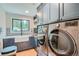 Well-lit laundry room with blue cabinetry, farmhouse sink, washer and dryer, and tiled backsplash at 2013 Swede Gulch Rd, Evergreen, CO 80439