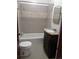 A cozy bathroom featuring a dark wood vanity, tiled shower, and toilet, with neutral tile flooring at 698 S 2Nd Ave, Brighton, CO 80601