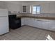 A spacious kitchen featuring tile floor, modern black appliances, ample white cabinetry and light countertops at 698 S 2Nd Ave, Brighton, CO 80601