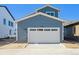 Exterior shot of blue two-story home featuring a large white garage door with windows at 2283 Serenidad St, Brighton, CO 80601