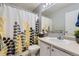 Bright bathroom with a yellow and gray patterned shower curtain and white vanity at 5327 Suffolk Cir, Castle Rock, CO 80104