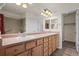 Bathroom with double sinks, wood cabinets, large mirrors, and a shower with a grab bar at 8258 S Sicily Ct, Aurora, CO 80016