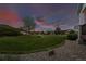 Expansive front yard with lush lawn, landscaping, and a beautiful sunset view at 8258 S Sicily Ct, Aurora, CO 80016