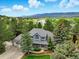 Picturesque aerial view of a two-story home with mature trees, lake, and mountain backdrop at 18590 Lower Lake Rd, Monument, CO 80132