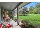 Welcoming covered porch featuring comfortable rocking chairs, manicured landscaping, and mature trees at 18590 Lower Lake Rd, Monument, CO 80132